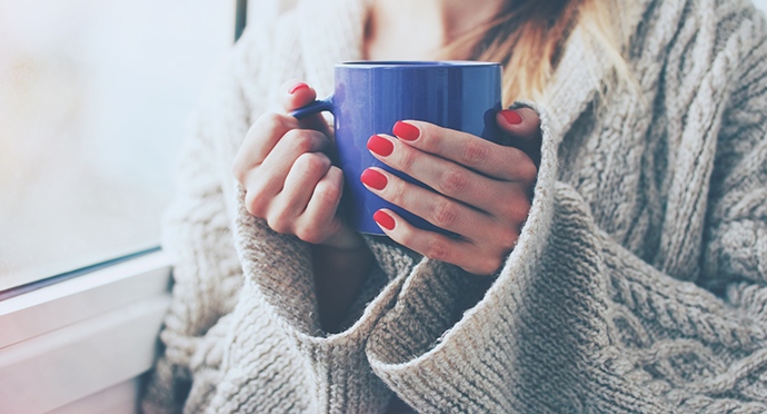 hands holding hot cup of coffee or tea in morning